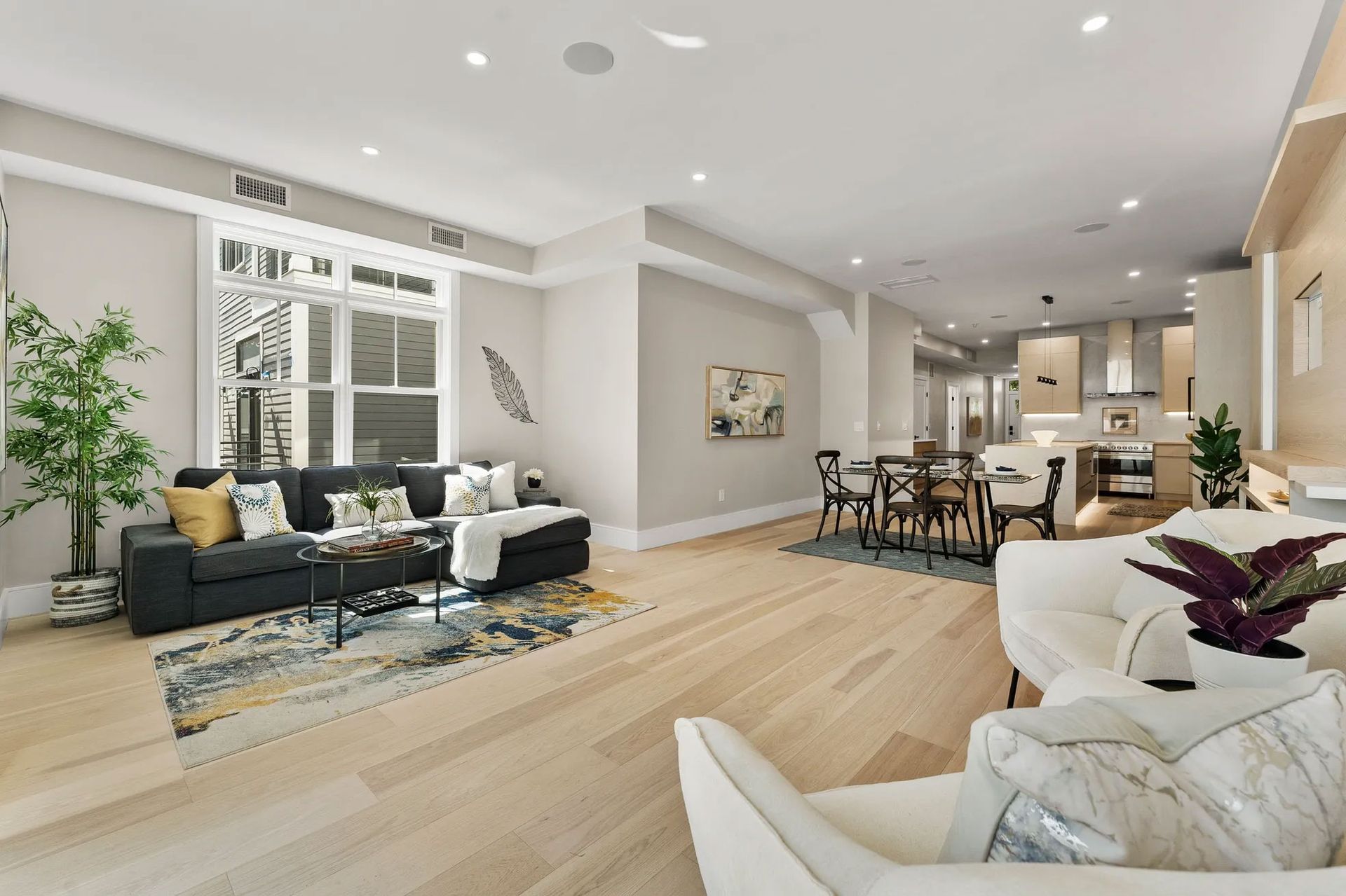 Spacious open-concept living space with light wood floors, a dark couch, and a dining area.