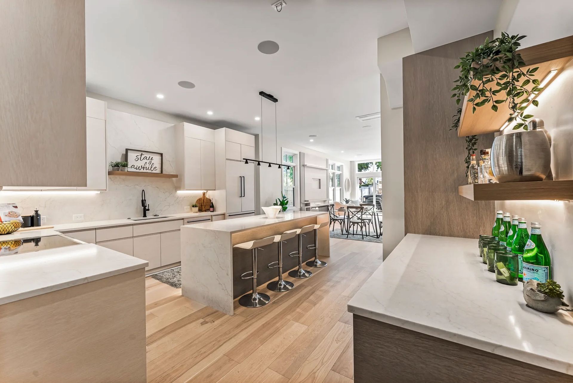 Modern kitchen with light wood floors, white cabinets, and island with bar stools.