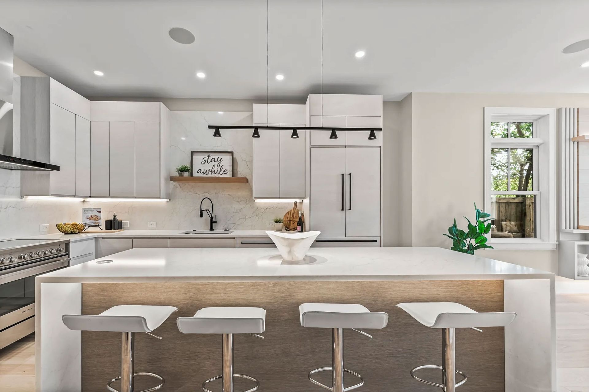 Modern kitchen with white cabinets, island with stools, and stainless steel appliances.