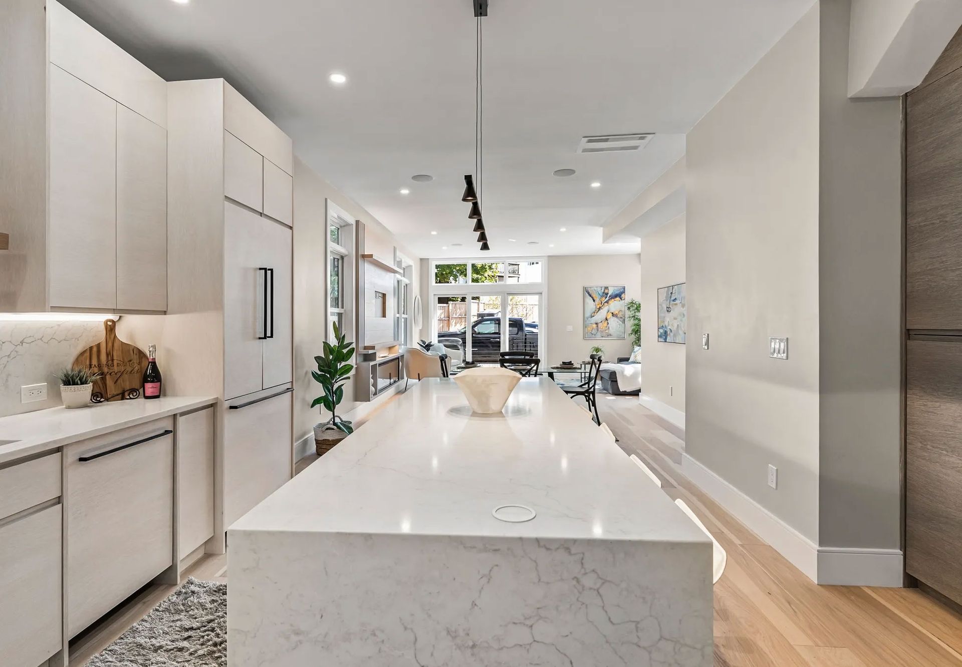 Modern kitchen with white cabinets, long island, and wood floors.