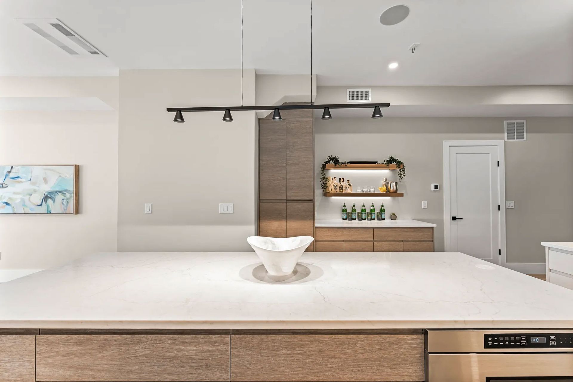 Modern kitchen with large island, pendant lights, cabinetry, and a built-in bar area.