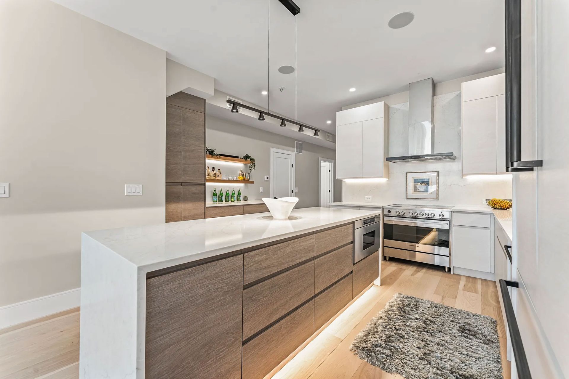 Modern kitchen with island, wooden cabinets, stainless steel appliances, and wood floors.