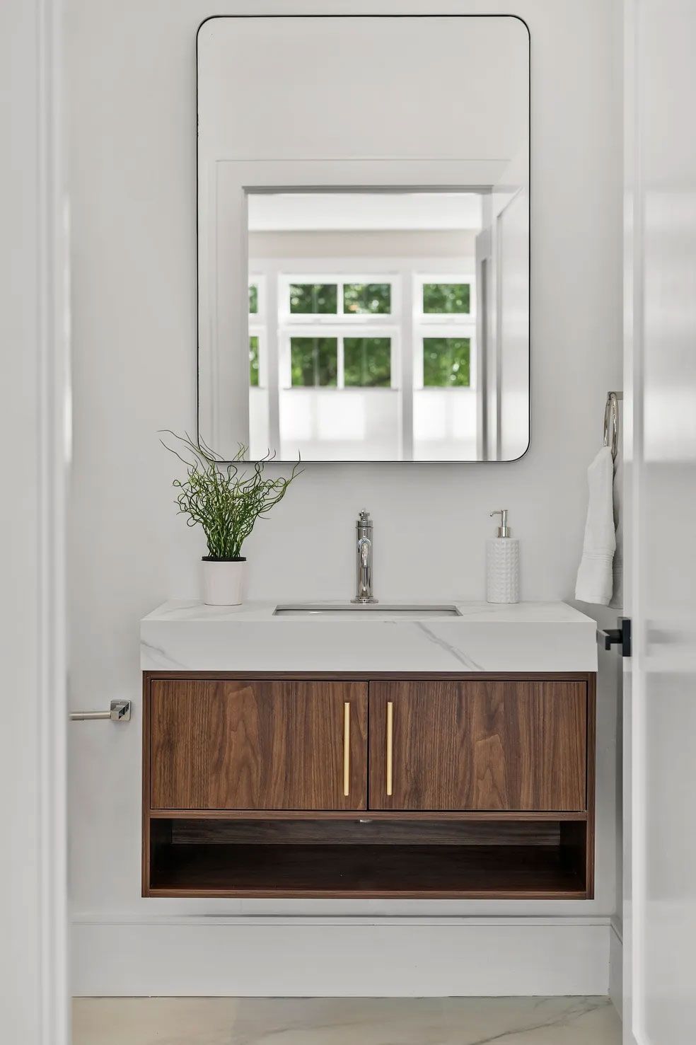 Modern bathroom vanity with a wood cabinet, marble countertop, and mirror.