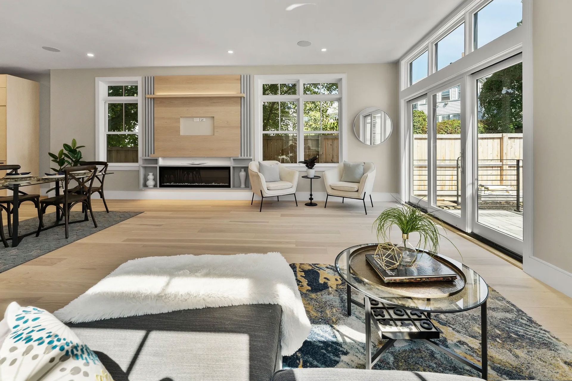 Bright, modern living room with light wood floors, fireplace, and large windows.