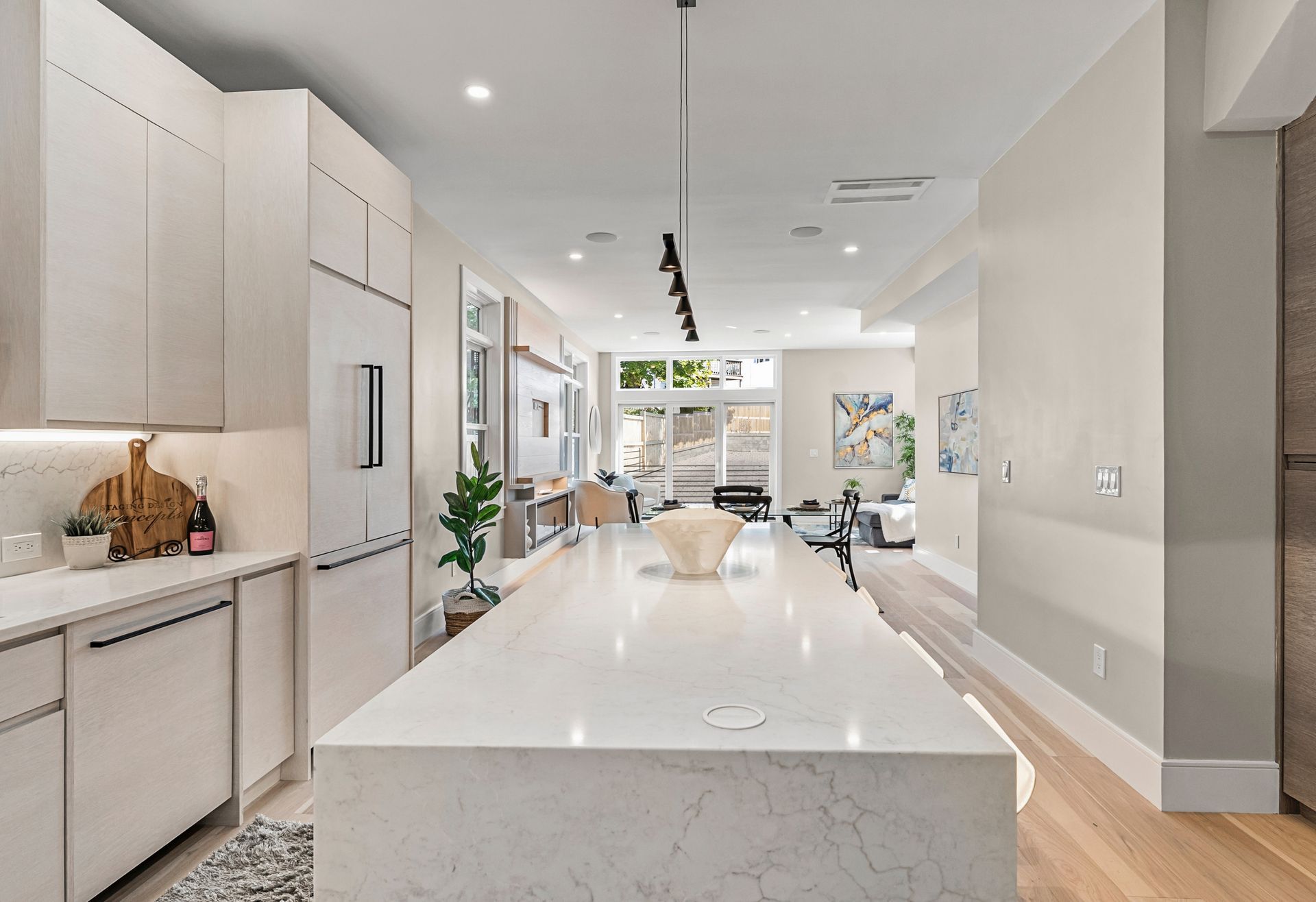 Modern kitchen with white cabinets, long island, and wood floors.