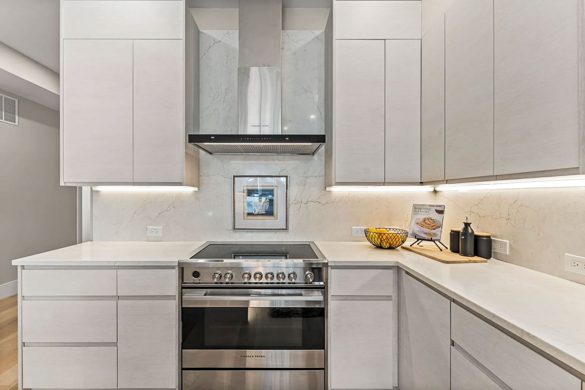 Modern white kitchen with stainless steel appliances, cabinets, and countertops.