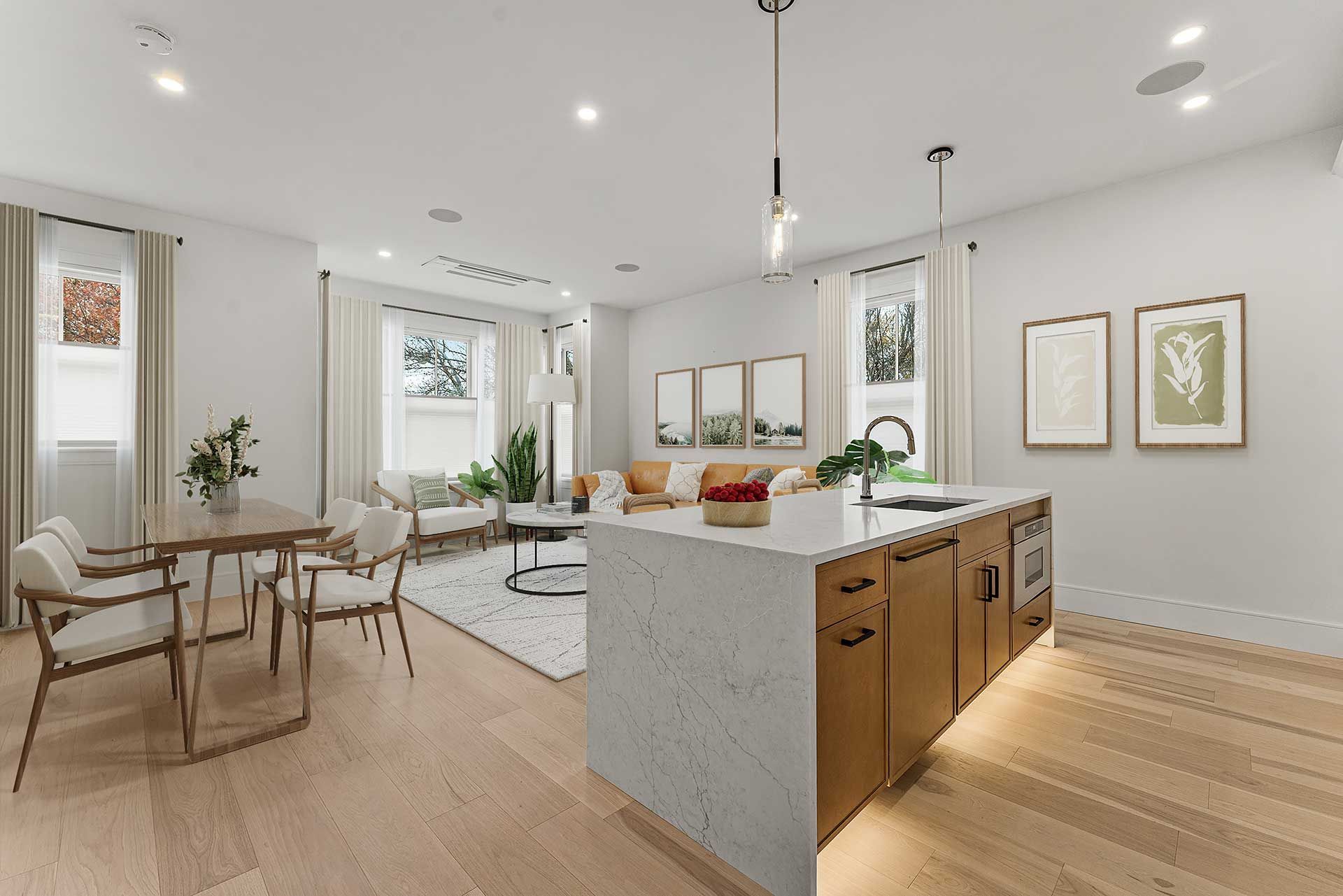 Open-concept kitchen and living area with island, light wood floors, and neutral furnishings.