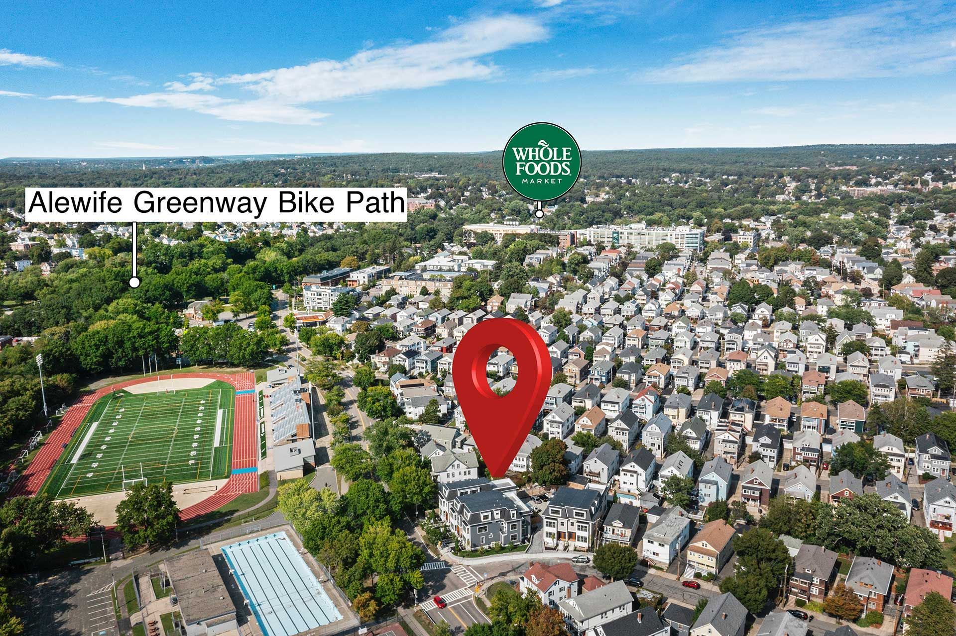 Aerial view of a neighborhood with a bike path, Whole Foods, and a football field.