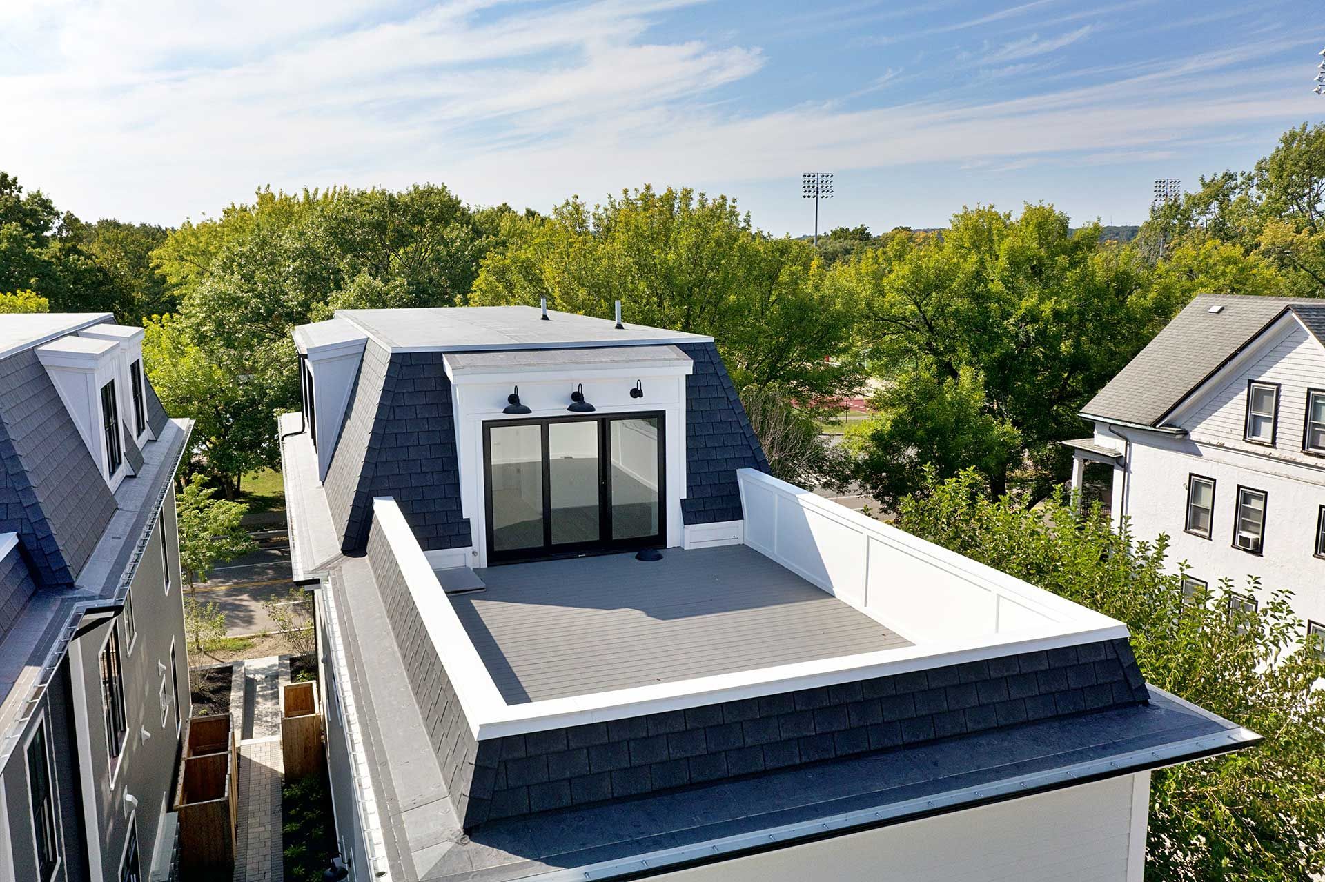 Rooftop deck with black roof and white trim, surrounded by trees.