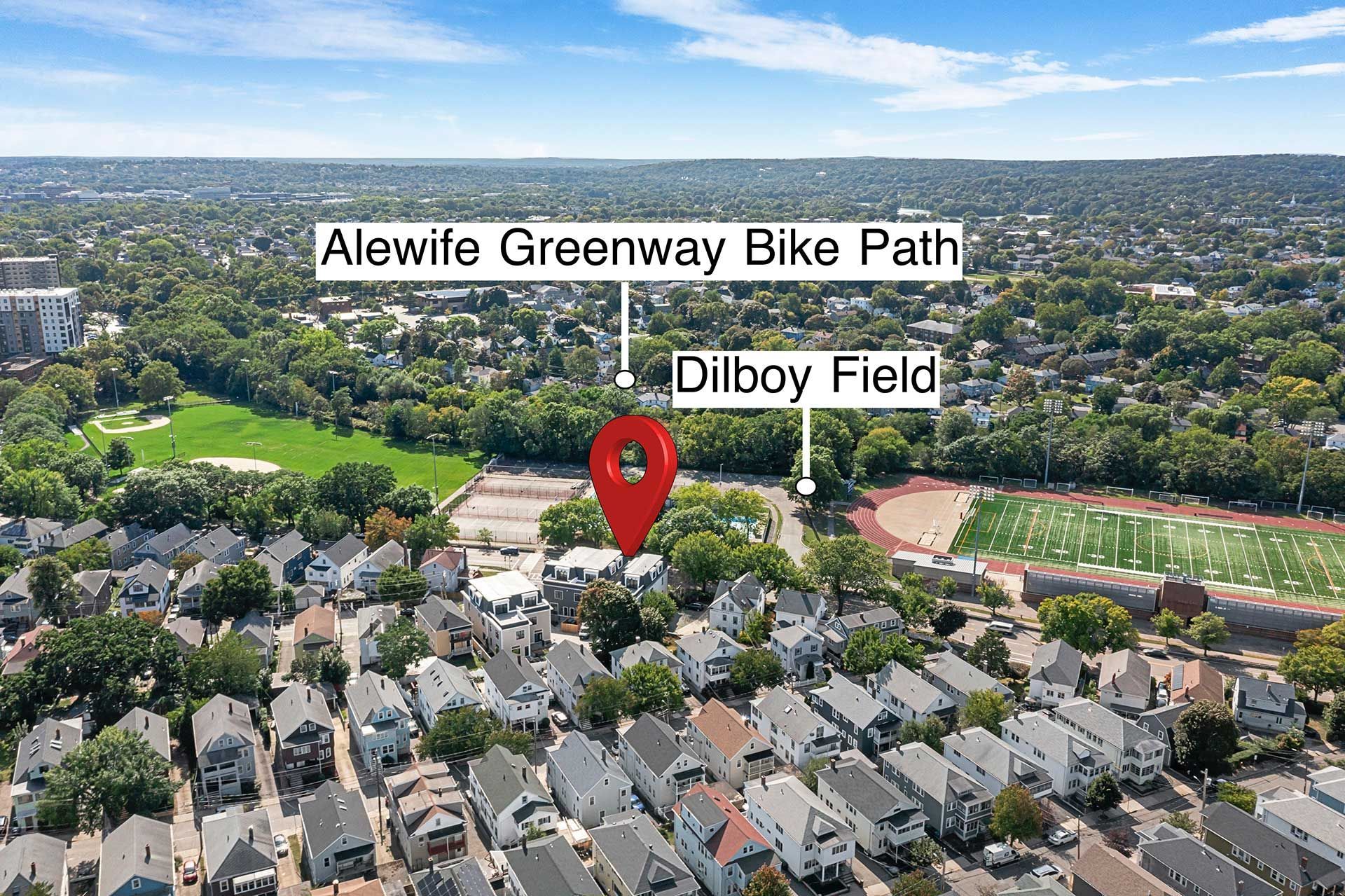 Aerial view of houses near a bike path and a sports field on a sunny day.