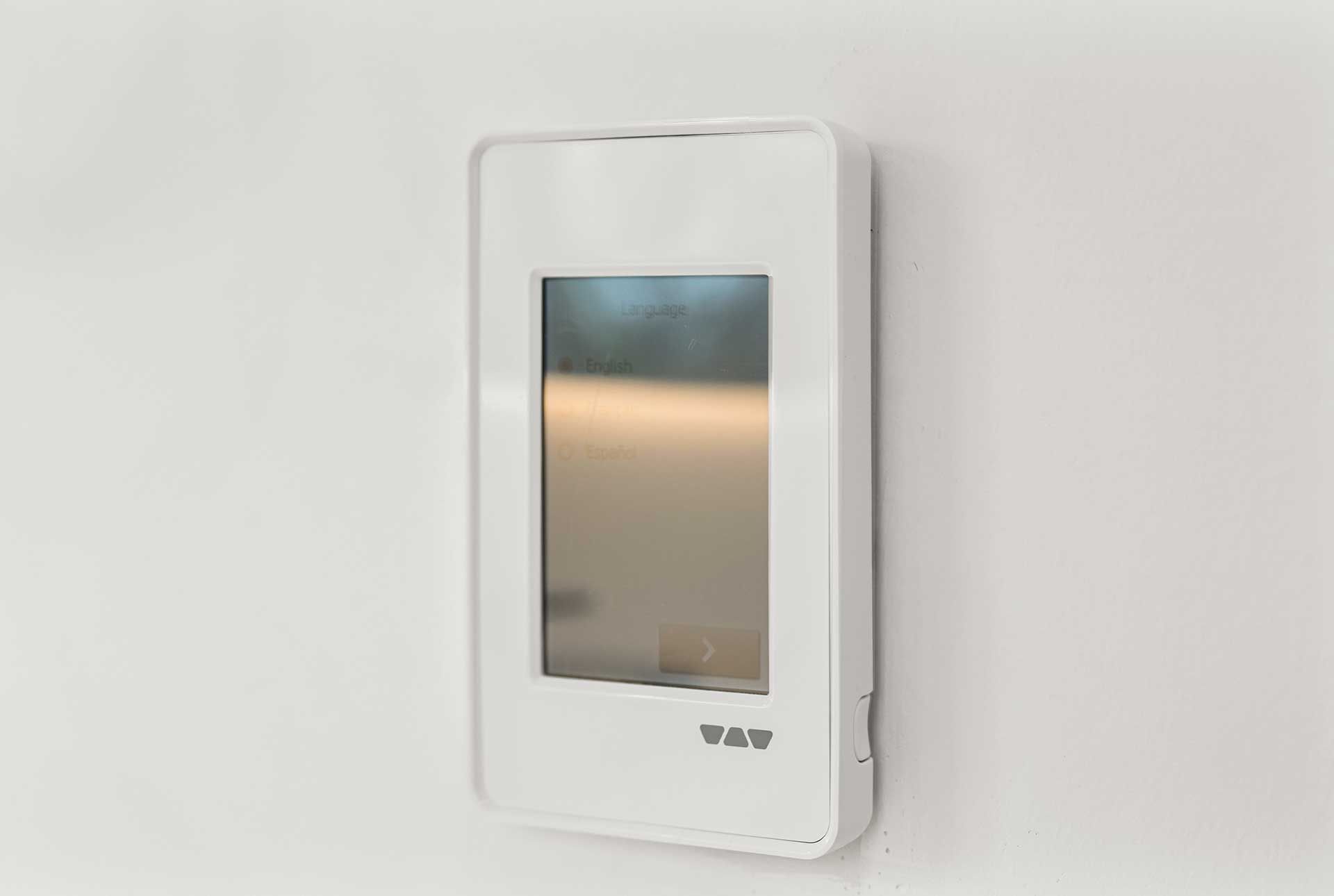 White thermostat with a screen mounted on a white wall.