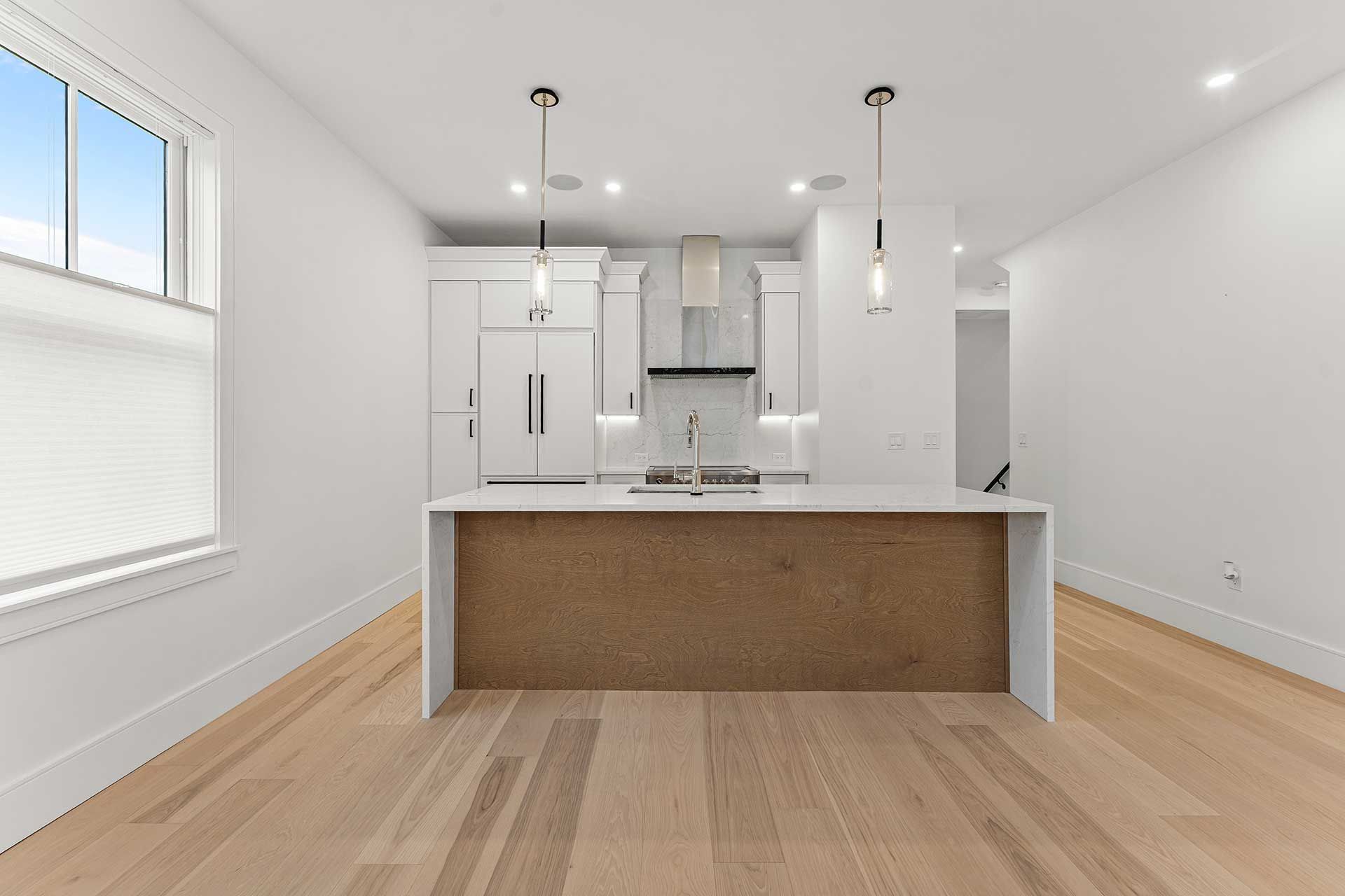Modern kitchen with white cabinets, wood island, and light wood floors.
