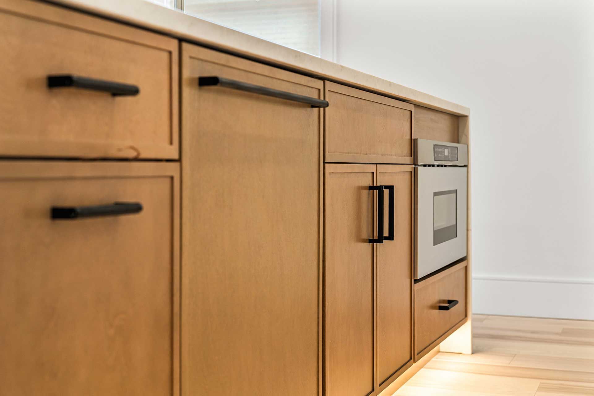 Wooden kitchen cabinets with black handles and a built-in oven.