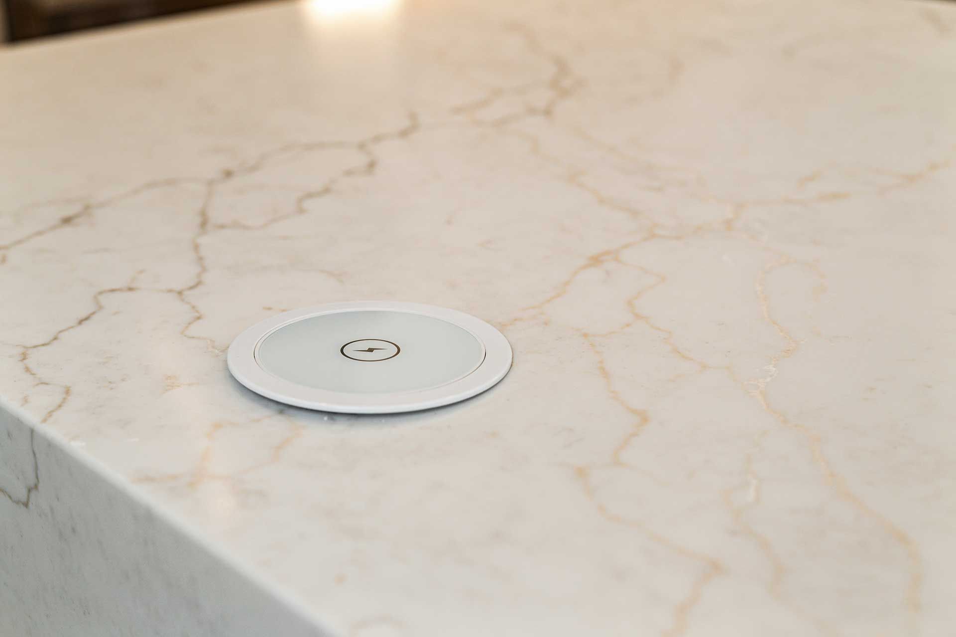 White countertop with a circular pop-up power outlet.