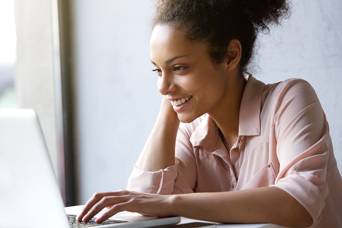 A woman is sitting at a table using a laptop computer.
