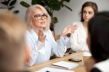 A woman is sitting at a table talking to a group of people.