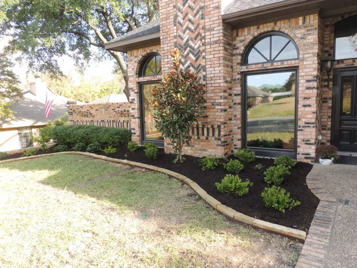 A brick house with a lush green lawn in front of it.