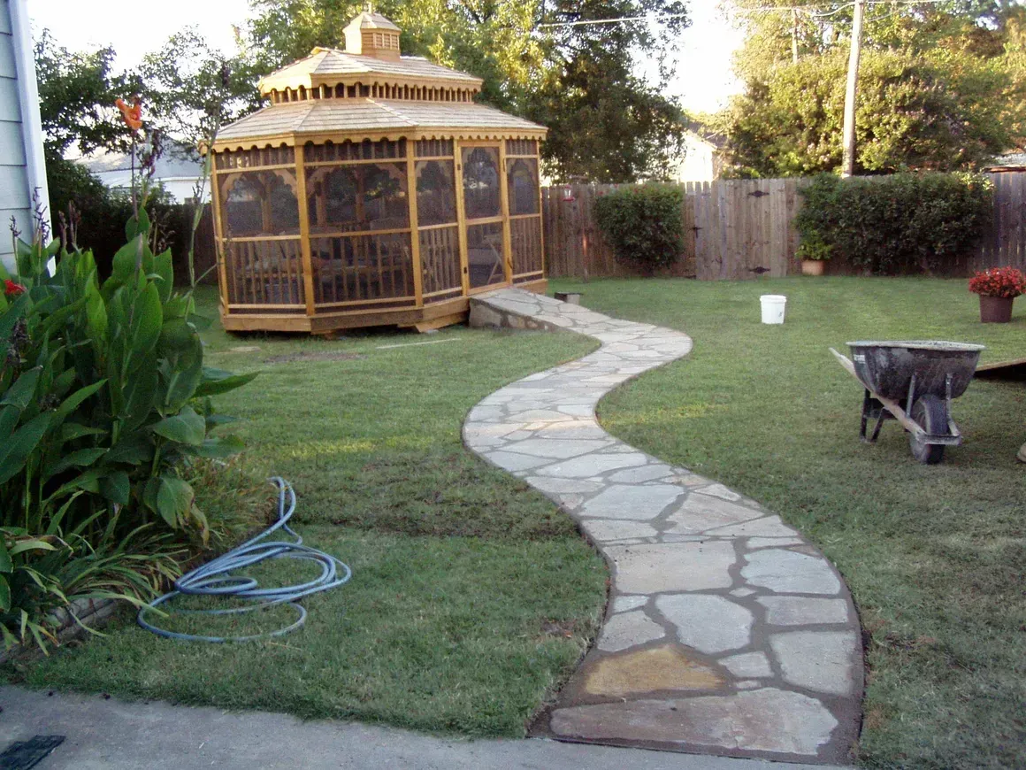 A patio with chairs , umbrellas , a bicycle and a bench.