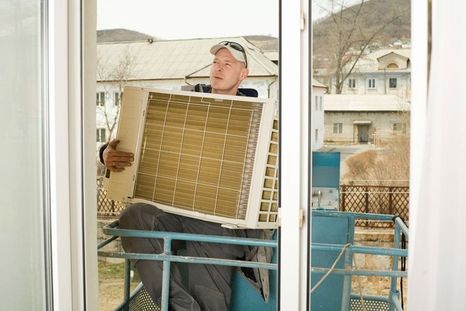Worker carrying a woven panel through a window opening on a balcony