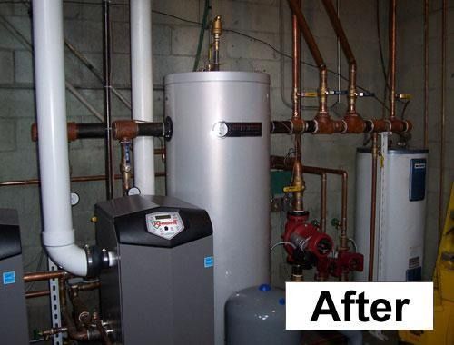 After photo of a basement utility room with a water heater, boiler, pipes, and tanks