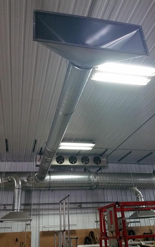 Industrial ceiling with large metal ductwork and fluorescent lights in a workshop or warehouse