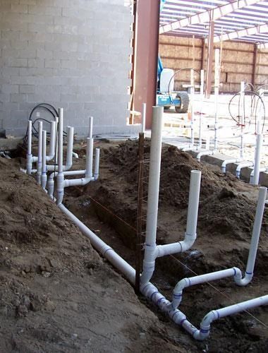 Plumbing pipes and vents installed in a construction site floor trench