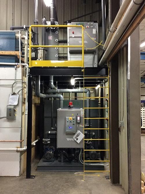 Industrial machinery room with yellow-railed platform, metal equipment, and a ladder in a utility space