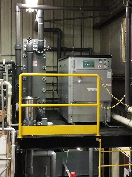 Industrial machine with yellow safety railings in a factory setting