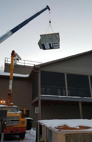 Crane lifting a small house module above a snowy building site