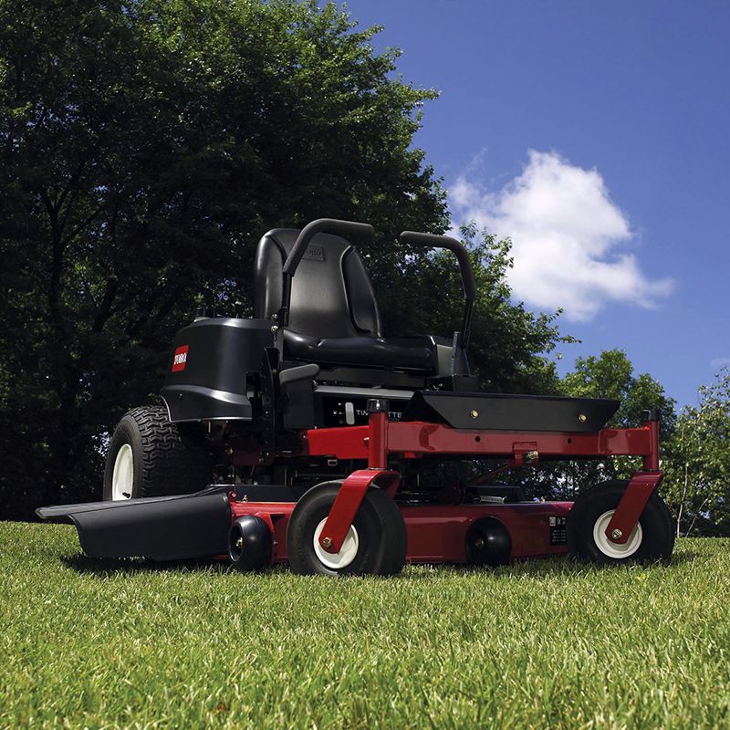 A red and black toro lawn mower is parked in the grass