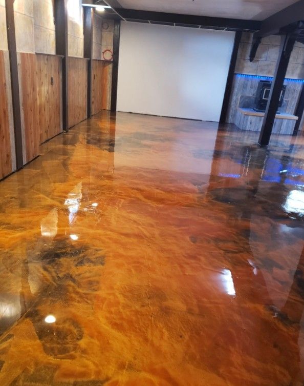 Orange and gold metallic epoxy floor in a large room with wood paneling on the walls and a projection screen.