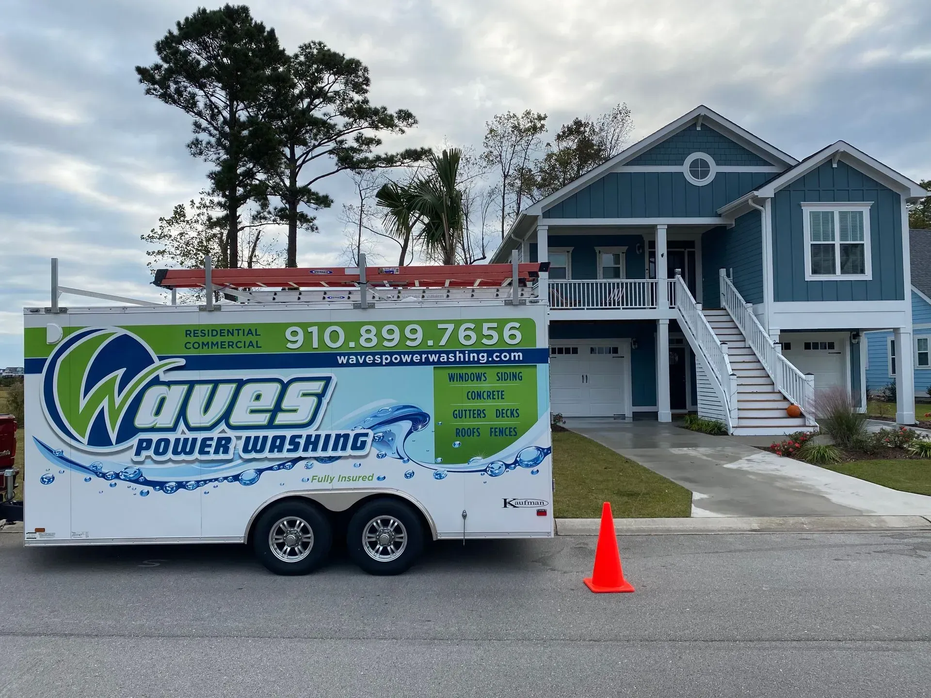Waves Power Washing trailer in front of blue house. Phone number 910-899-7656.