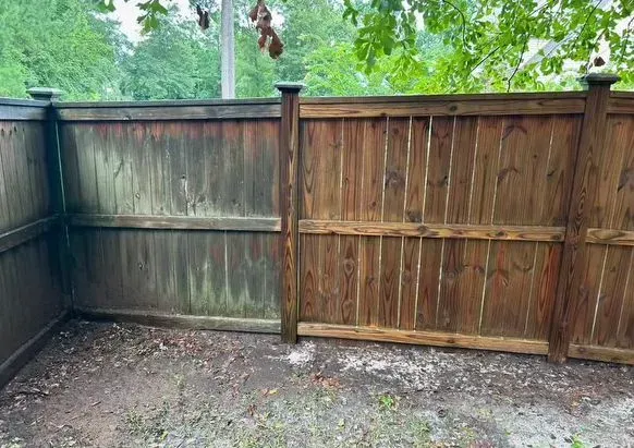 Fence, half cleaned, showing comparison of dirty and clean wood. Outdoors, gray/brown.