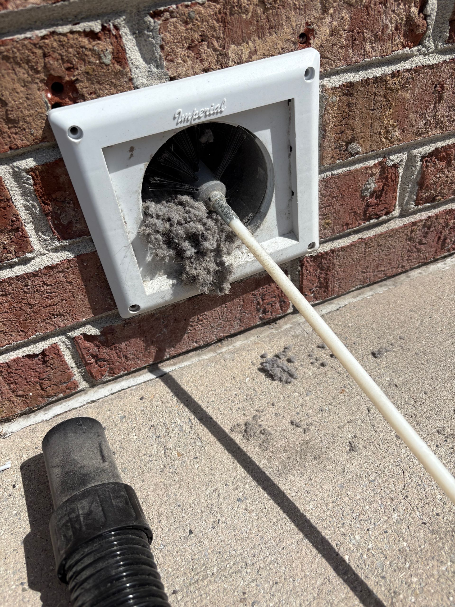 Cleaning a dryer vent with a brush, revealing a large buildup of lint.