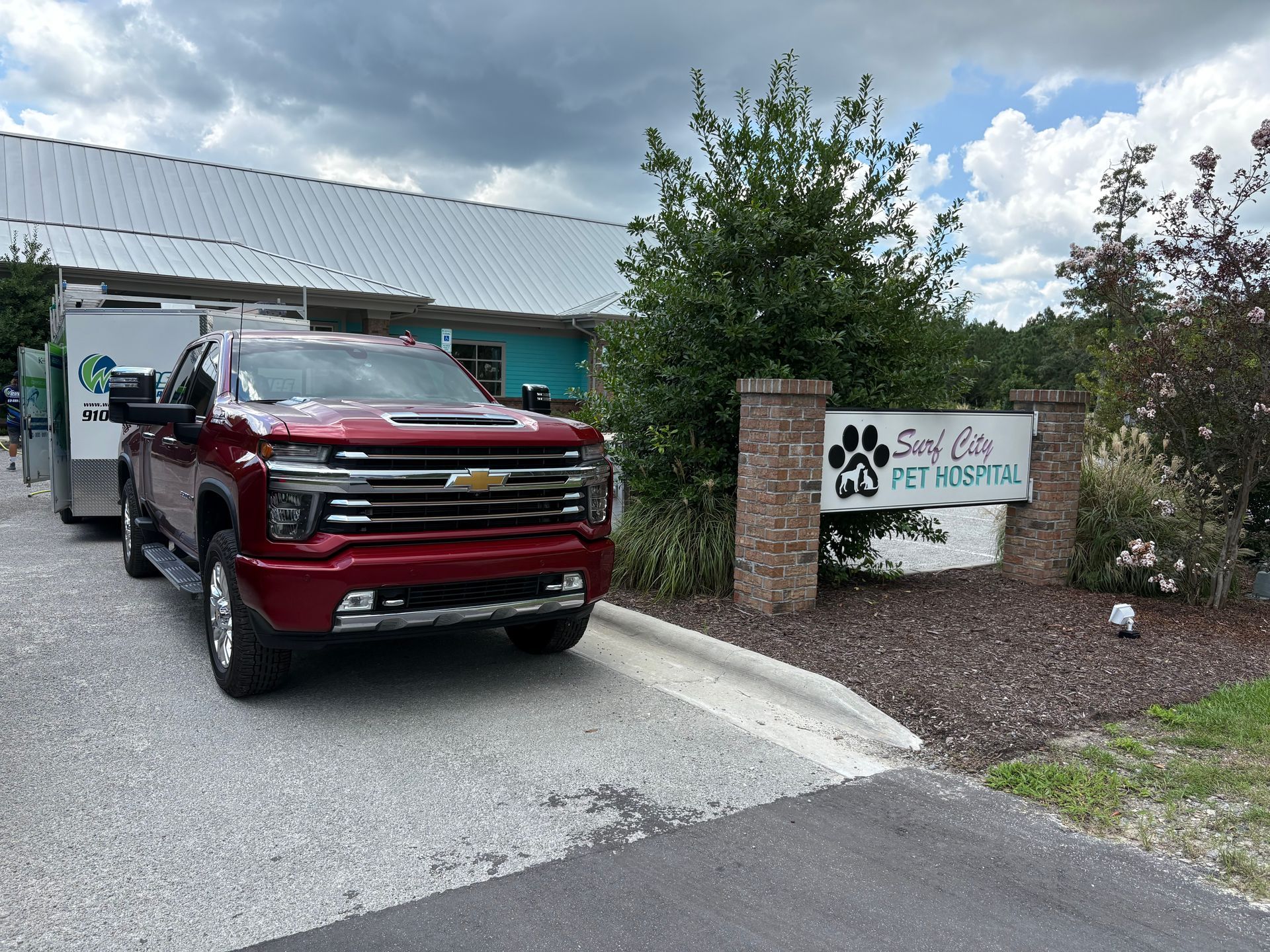 Red truck pulling a trailer in front of a sign for Save Cats Pet Rescue.