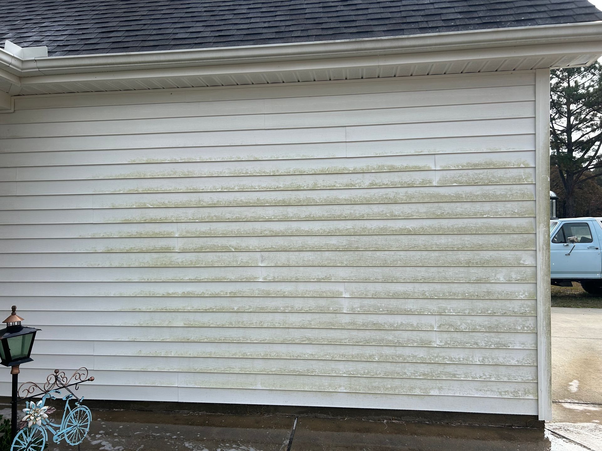 White vinyl siding on a house, partially cleaned with visible dirt and grime.