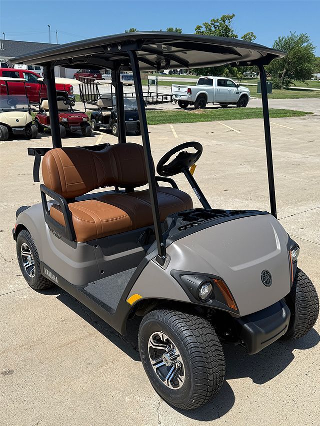 Dark gray Yamaha golf cart parked outside on a sunny day. It has black features, silver wheels, and a roof.