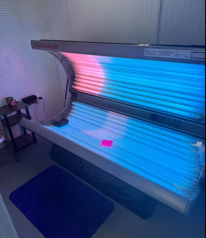 A tanning bed with blue and pink lights in a room.