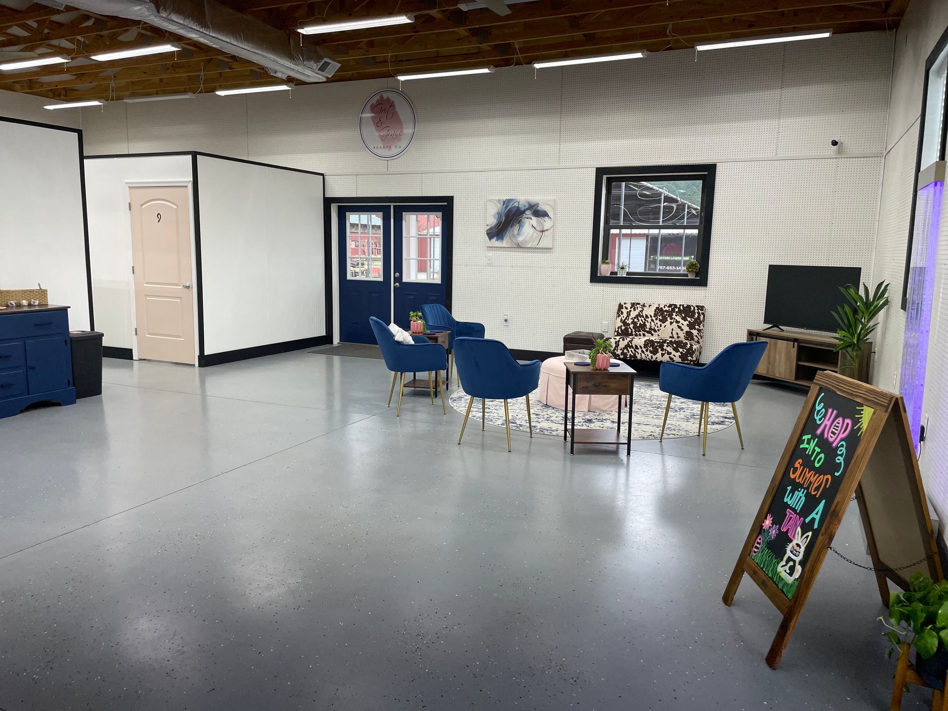 A large room with a couch , chairs , tables and a sign.