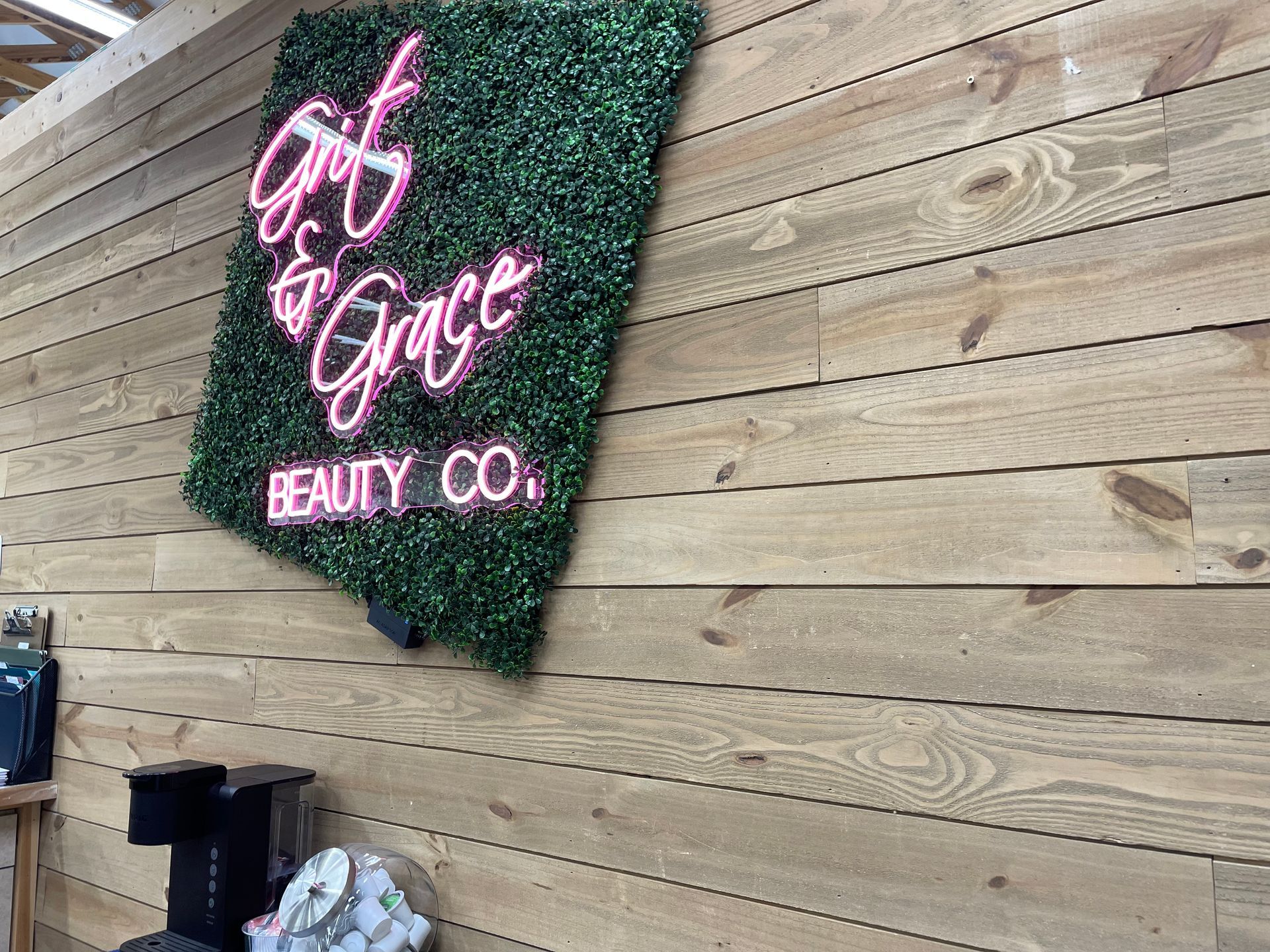 A neon sign is hanging on a wooden wall.