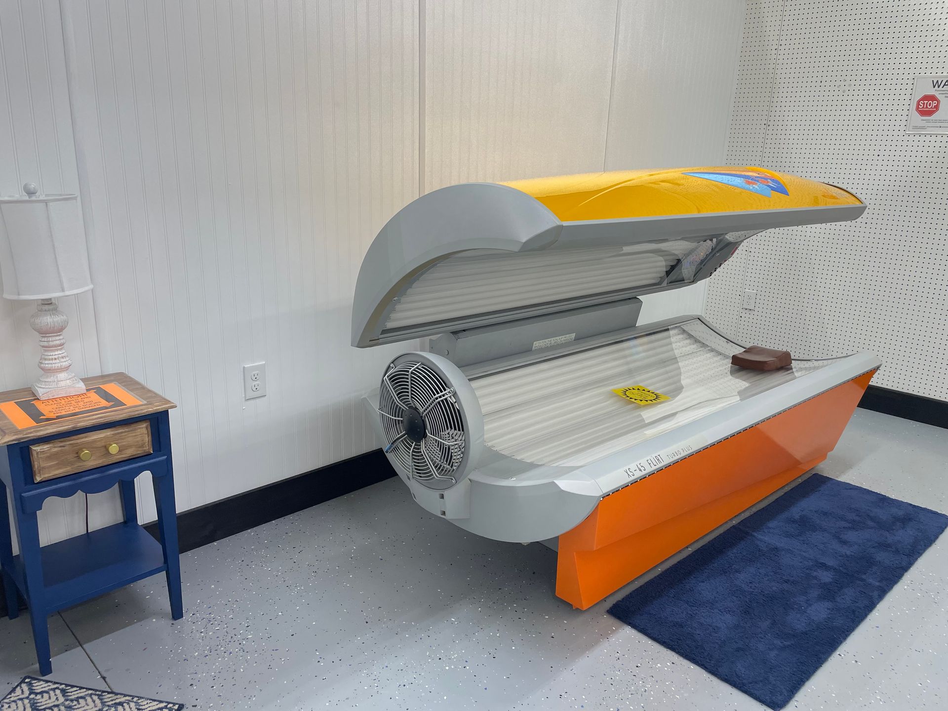 A tanning bed is sitting in a room next to a table.