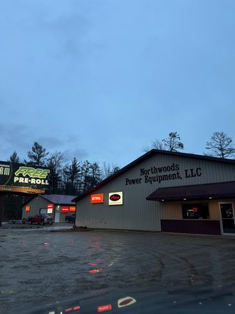 A commercial building titled Northwoods Power Equipment, LLC, with a lit sign for pre-rolls on an adjacent property.