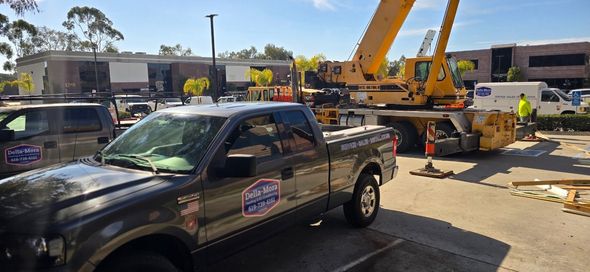 A construction site with a large crane, pickup truck, and workers near a building.