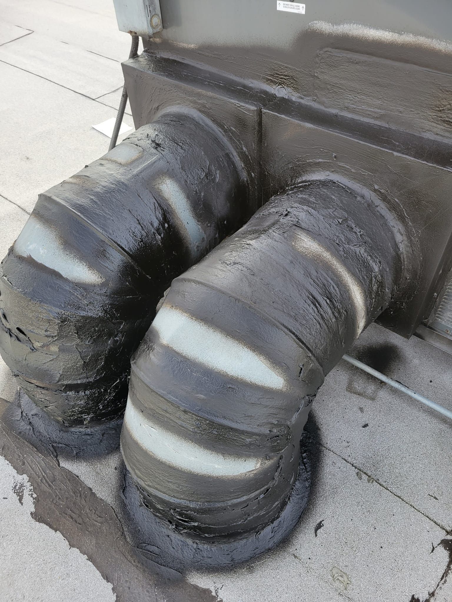 Two black insulated air ducts with white stripes, connected to a rooftop unit.