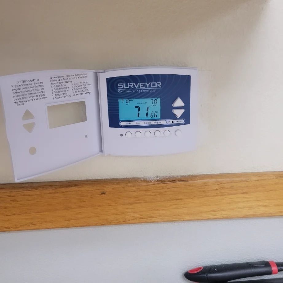 White thermostat on wall displays 71 degrees. Instruction booklet attached.