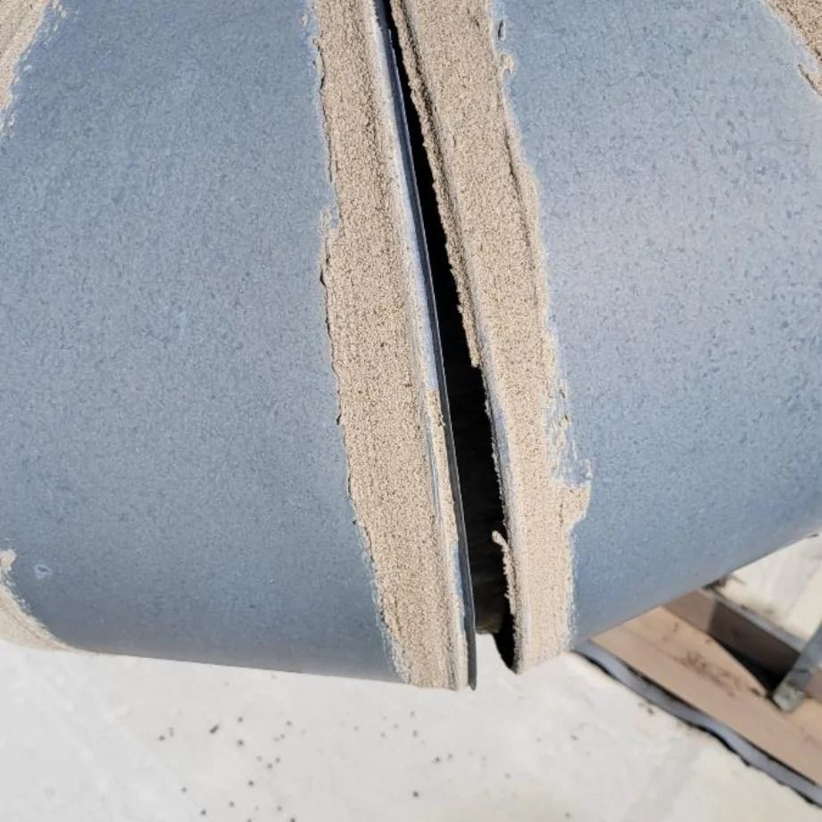 Close-up of two pieces of blue, textured material with sandy edges separated by a gap.