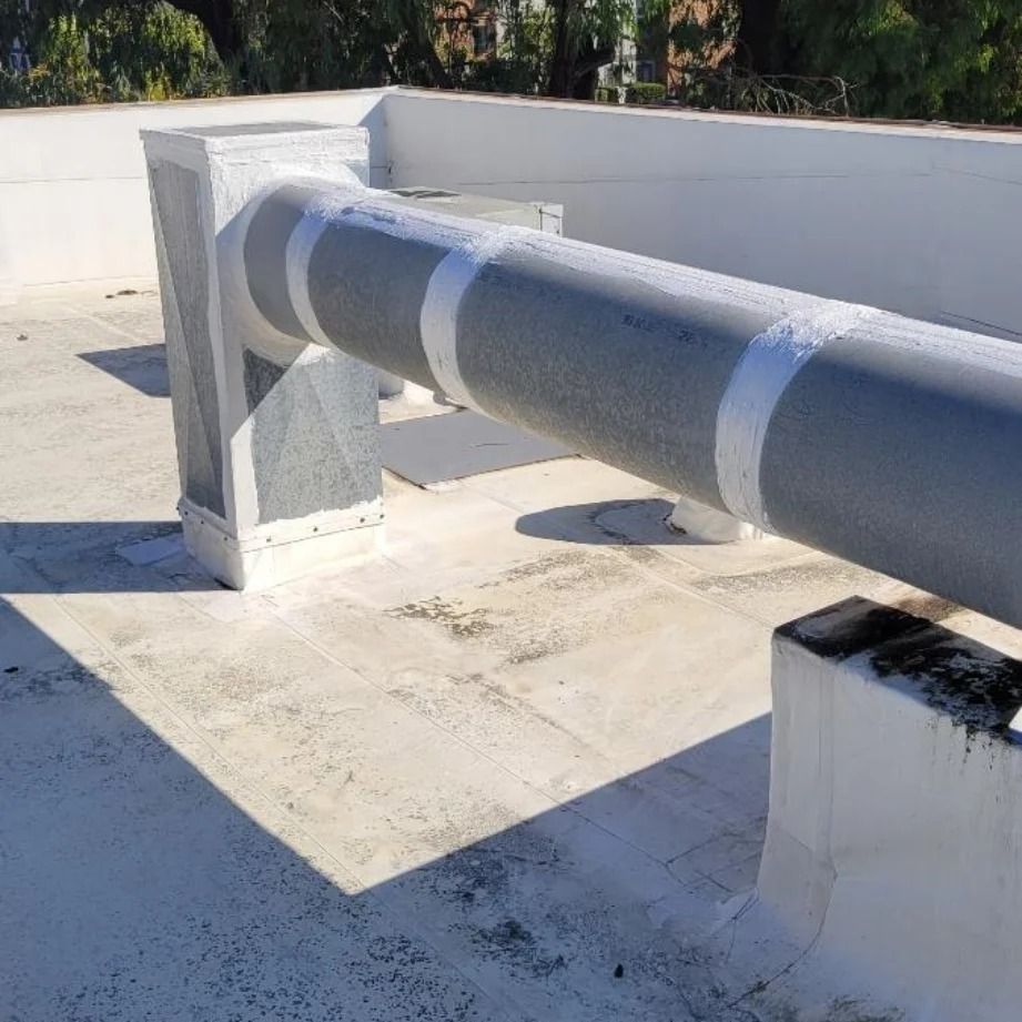 Gray pipe with white tape on a white roof, supported by white pillars.