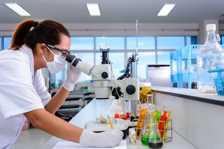 A female scientist is looking through a microscope in a laboratory.