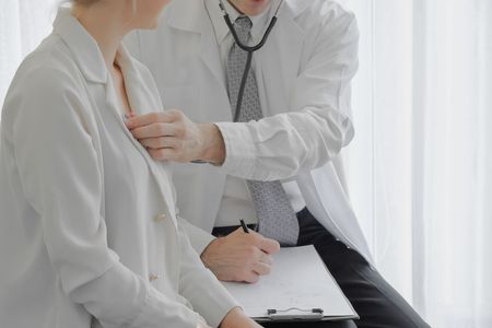 A doctor is examining a patient 's chest with a stethoscope.