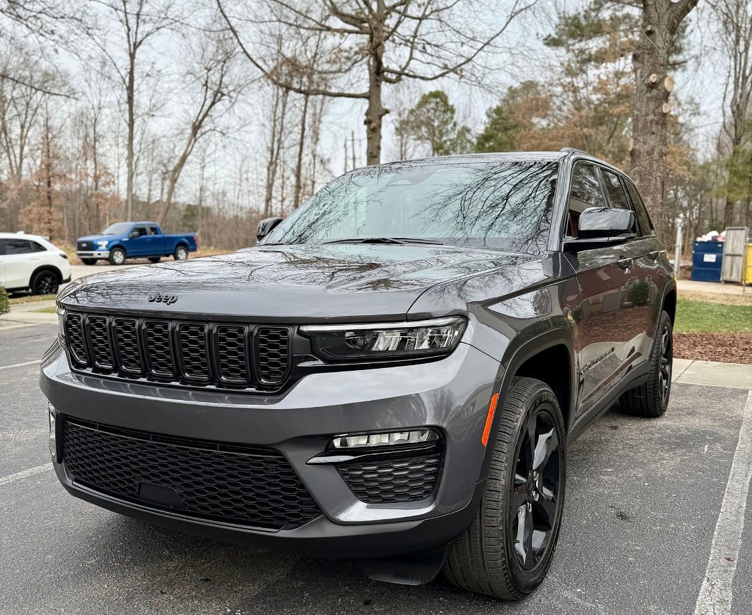 Dark gray Jeep Grand Cherokee parked outside, trees in the background.